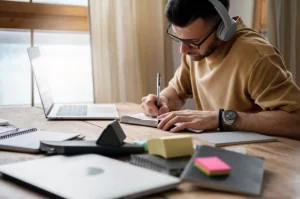 Homem estudando concentrado para o vestibular com materiais de estudo sobre a mesa