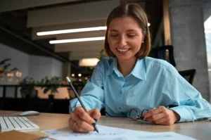 Aluna fazendo anotações em um caderno enquanto organiza o planejamento financeiro para estudar com financiamento FIES