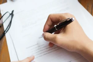 mão assinando contrato de estágio conforme a lei de estágio